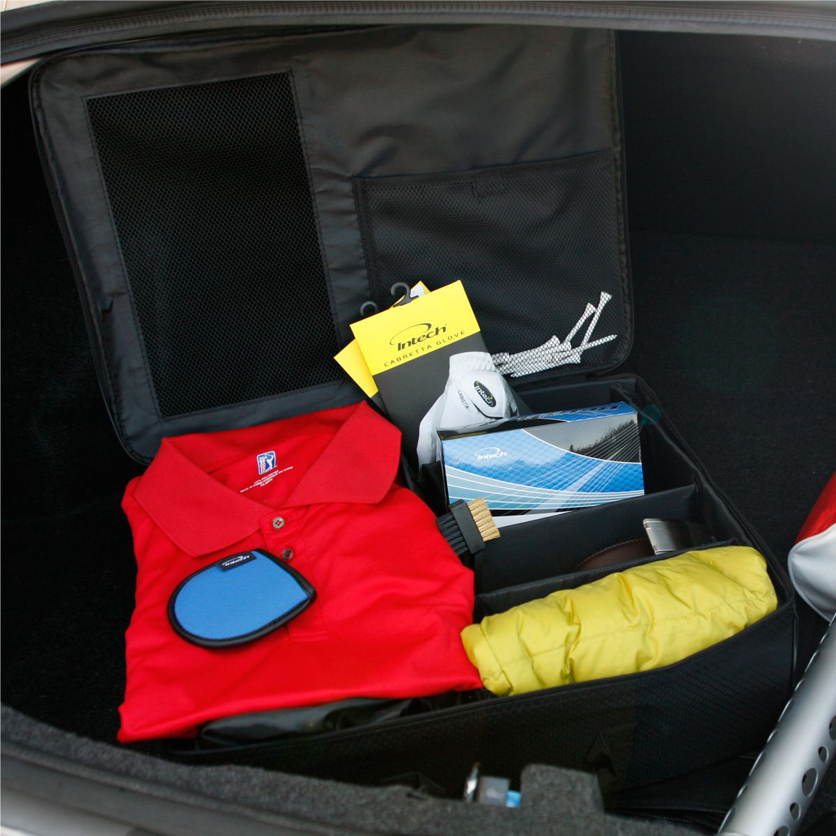 opened Intech Single Row Golf Trunk Organizer inside a car trunk with golf apparel inside