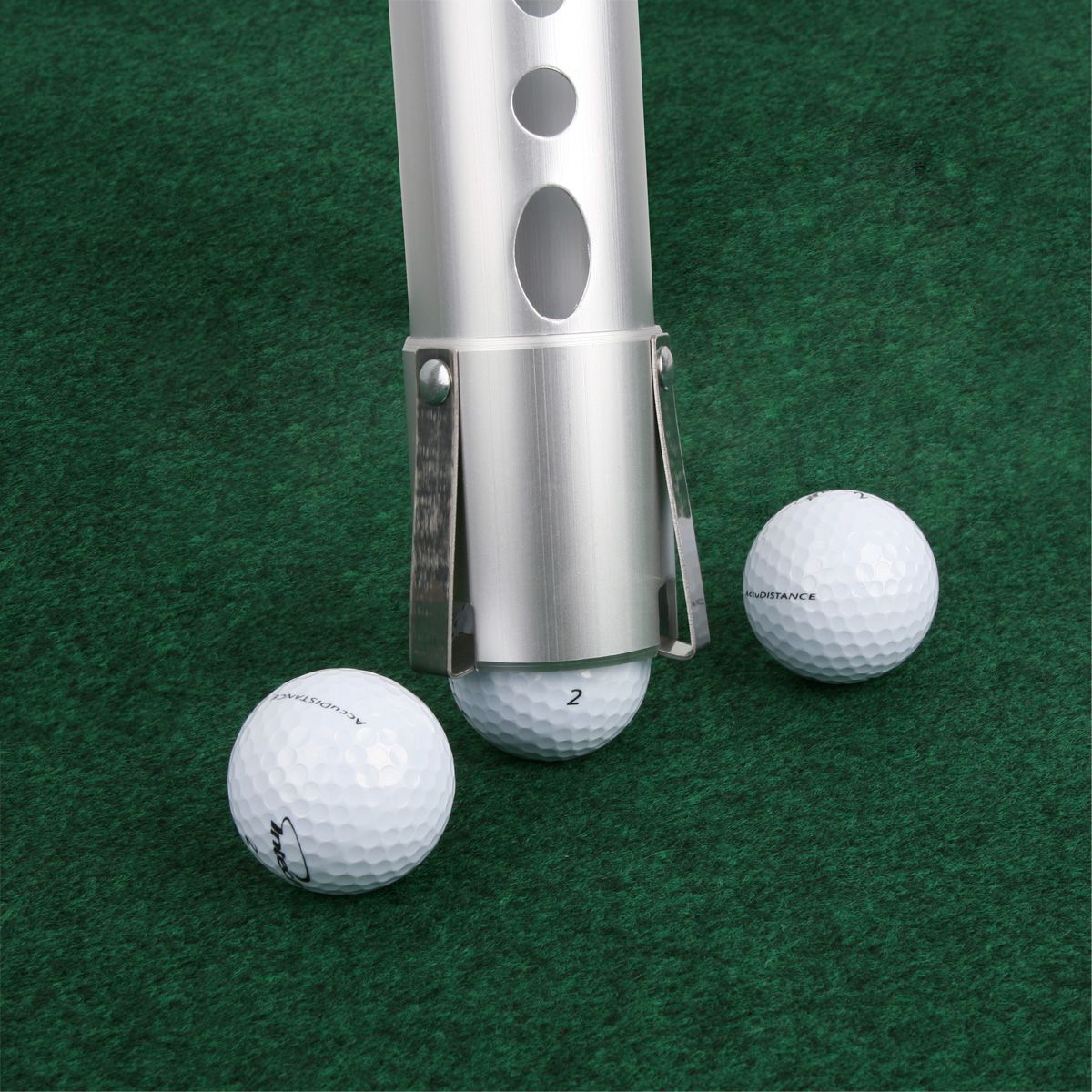 an Intech Golf Ball Shag Bag pressing down on the middle of 3 white golf balls on a green surface